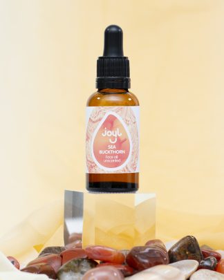 Single oil dropper bottle on acrylic cube with peach background and stones